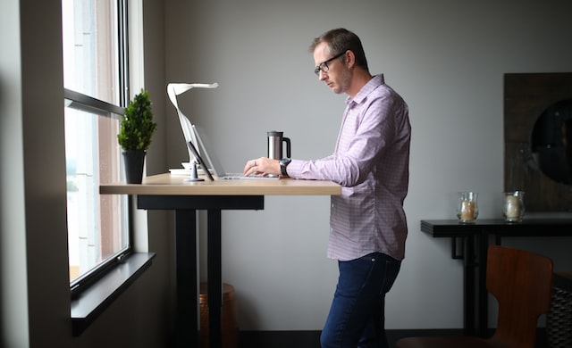  A man using an adjustable standing desk.