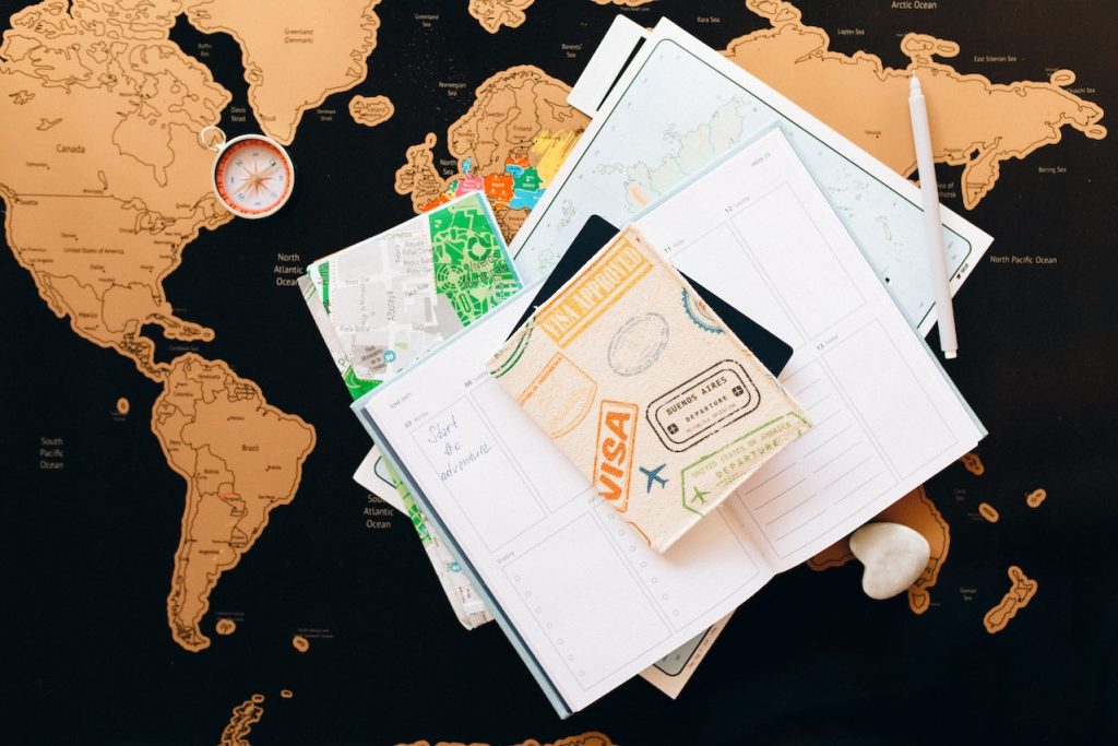 A lot of papers, a passport, and a visa on a world map.