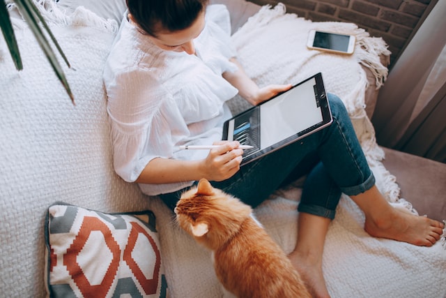 A woman being distracted by her cat while working.