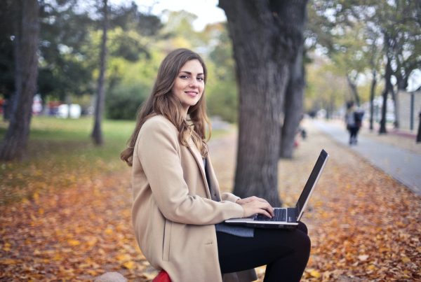 A woman typing on a laptop in a park.