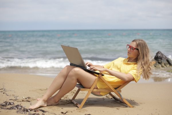 A woman working on her laptop while on the beach